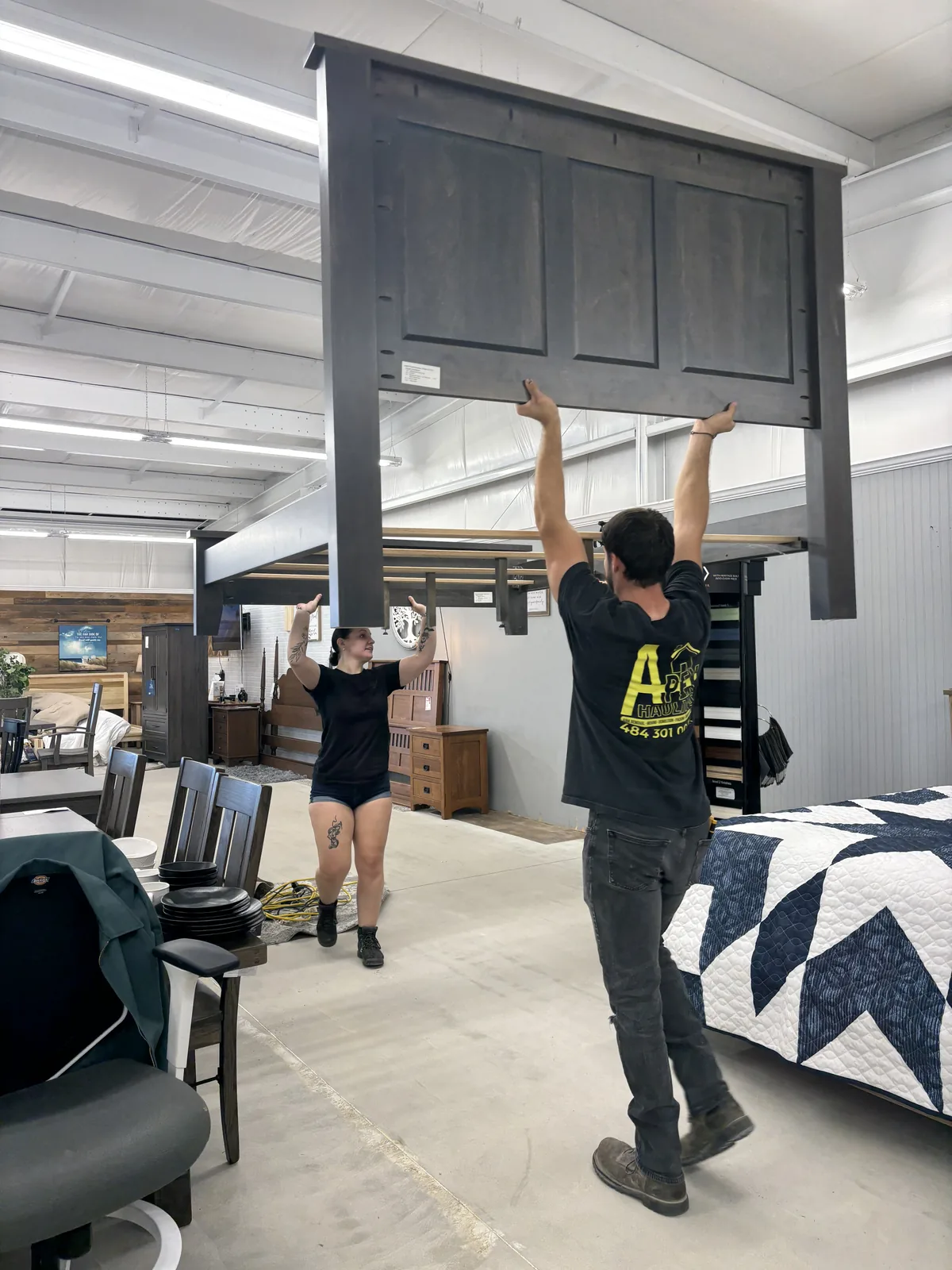 Two movers carrying a headboard through a doorway